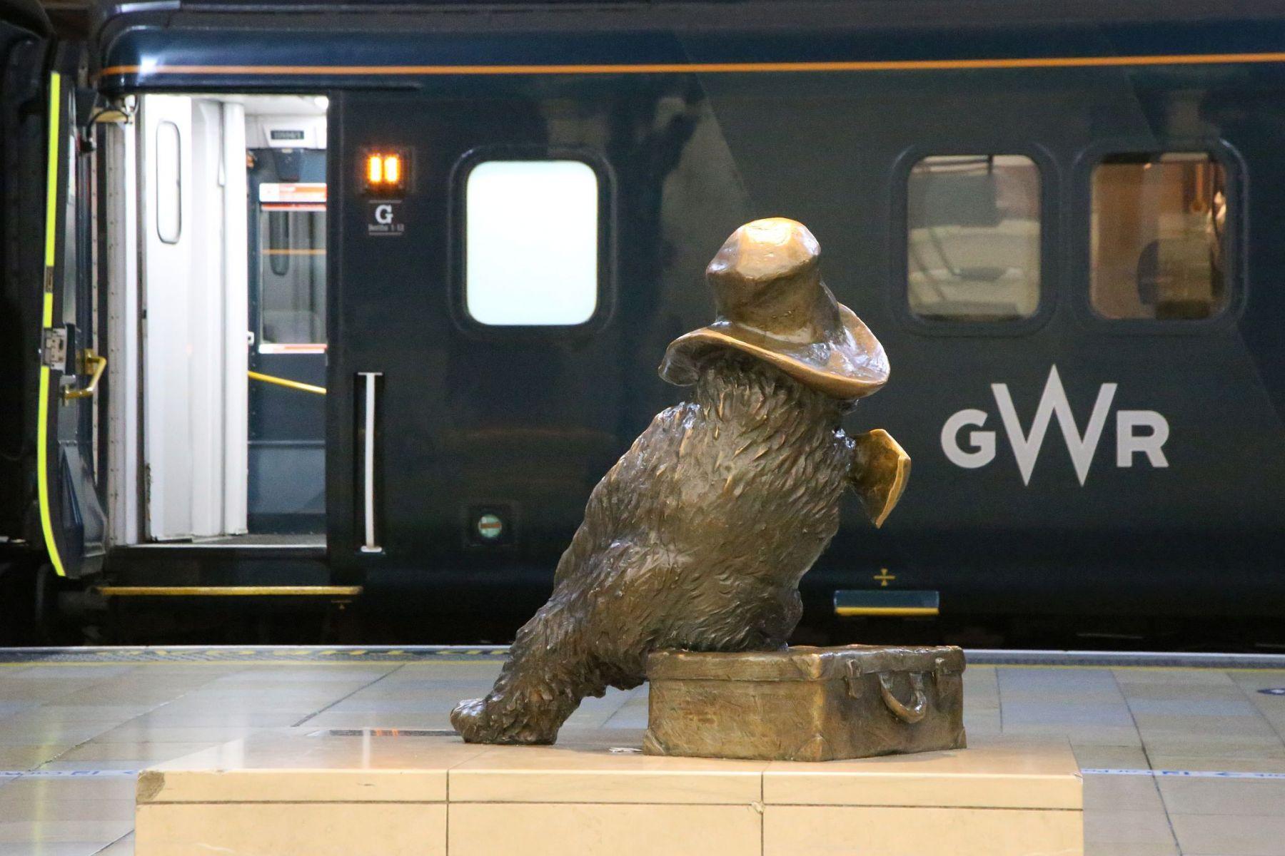 Paddington Bear statue looks at The Great Western Night Riviera Sleeper Train at London Paddington railway station