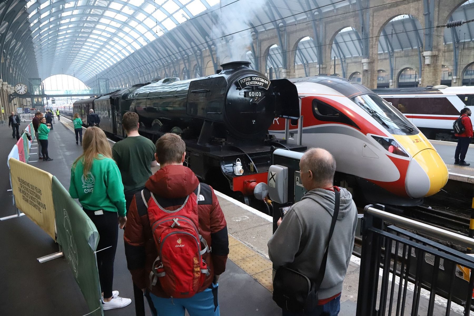 Crowd on platform next to steam engine Flying Scotsman with an Azuma train next to it. Flying Scotsman steam locomotive at King's Cross railway station platform 8 for the 170th anniversary of the station's opening and the start of Flying Scotsman's 100th birthday celebrations