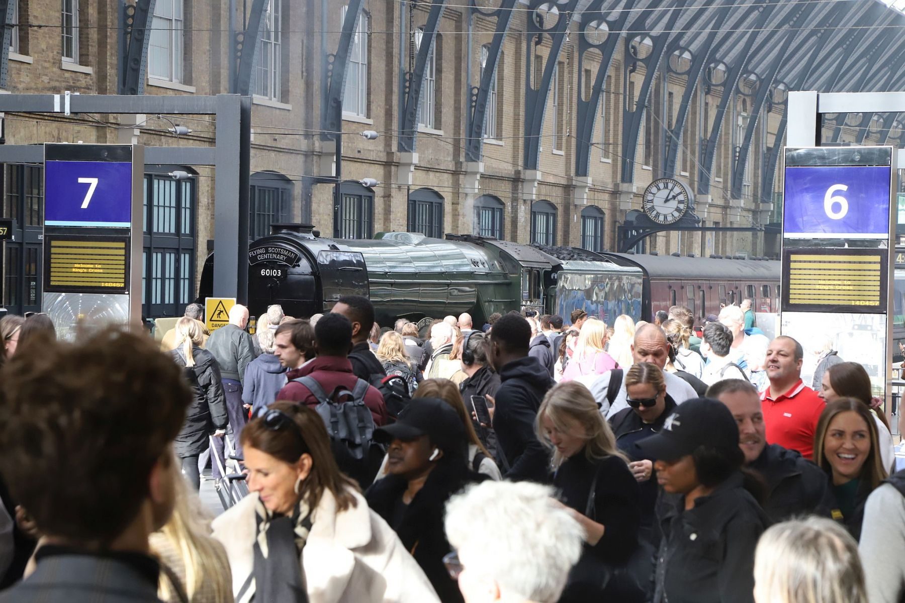 Crowds of passengers pass Flying Scotsman at King's Cross. Flying Scotsman steam locomotive at King's Cross railway station platform 8 for the 170th anniversary of the station's opening and the start of Flying Scotsman's 100th birthday celebrations