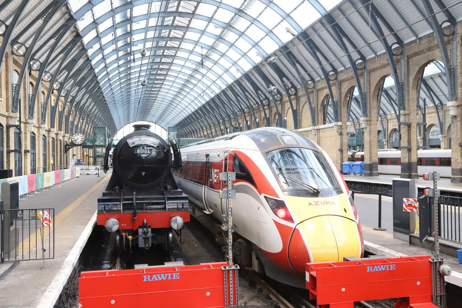 Flying Scotsman and an Azuma railway train under the arched roof of King's Cross at the buffers. Flying Scotsman steam locomotive at King's Cross railway station platform 8 for the 170th anniversary of the station's opening and the start of Flying Scotsman's 100th birthday celebrations