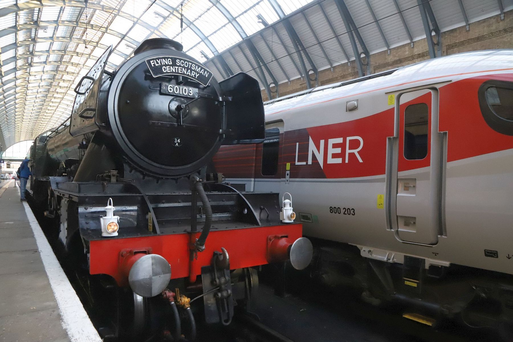 Flying Scotsman next to an Azuma under the arched roof of the King's Cross train shed. Flying Scotsman steam locomotive at King's Cross railway station platform 8 for the 170th anniversary of the station's opening and the start of Flying Scotsman's 100th birthday celebrations