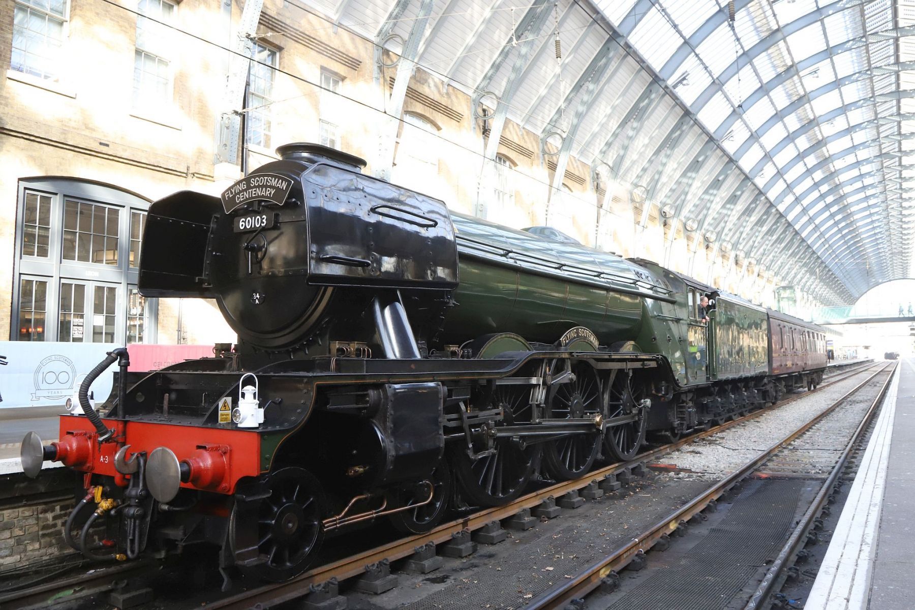 Flying Scotsman and support coach under the arched roof of the King's Cross train shed. Flying Scotsman steam locomotive at King's Cross railway station platform 8 for the 170th anniversary of the station's opening and the start of Flying Scotsman's 100th birthday celebrations