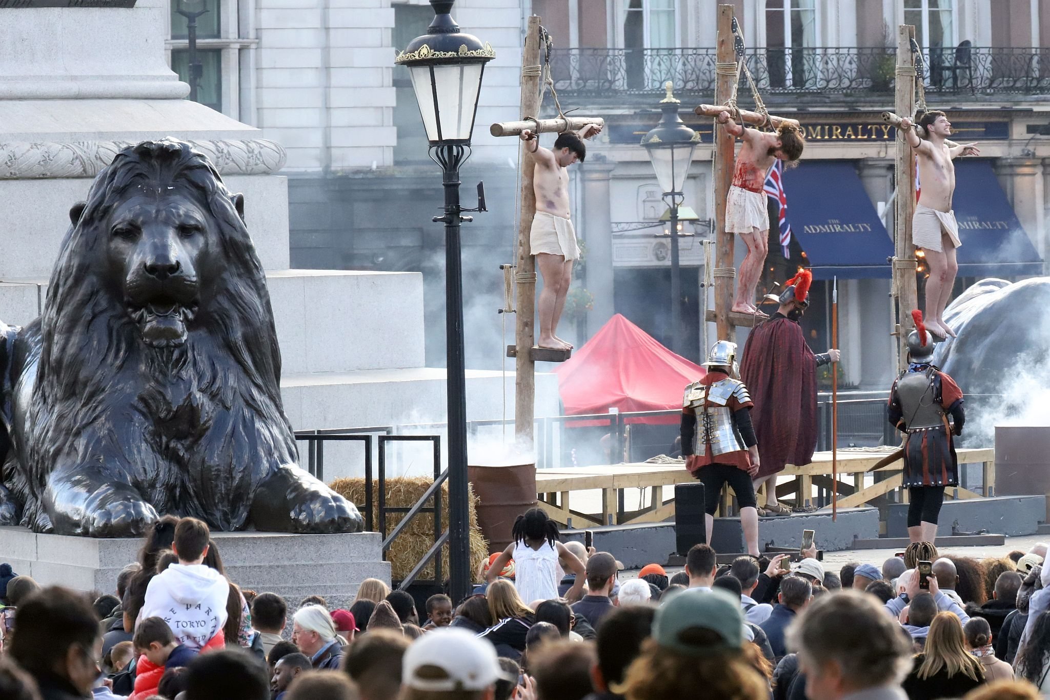 The Good Friday Wintershall Easter Passion Play "The Passion of Jesus" presented at Trafalgar Square in London. 7th April 2023. The famous Trafalgar Square lions by Edwin Landseer stand silent witness to Christ on the Cross.