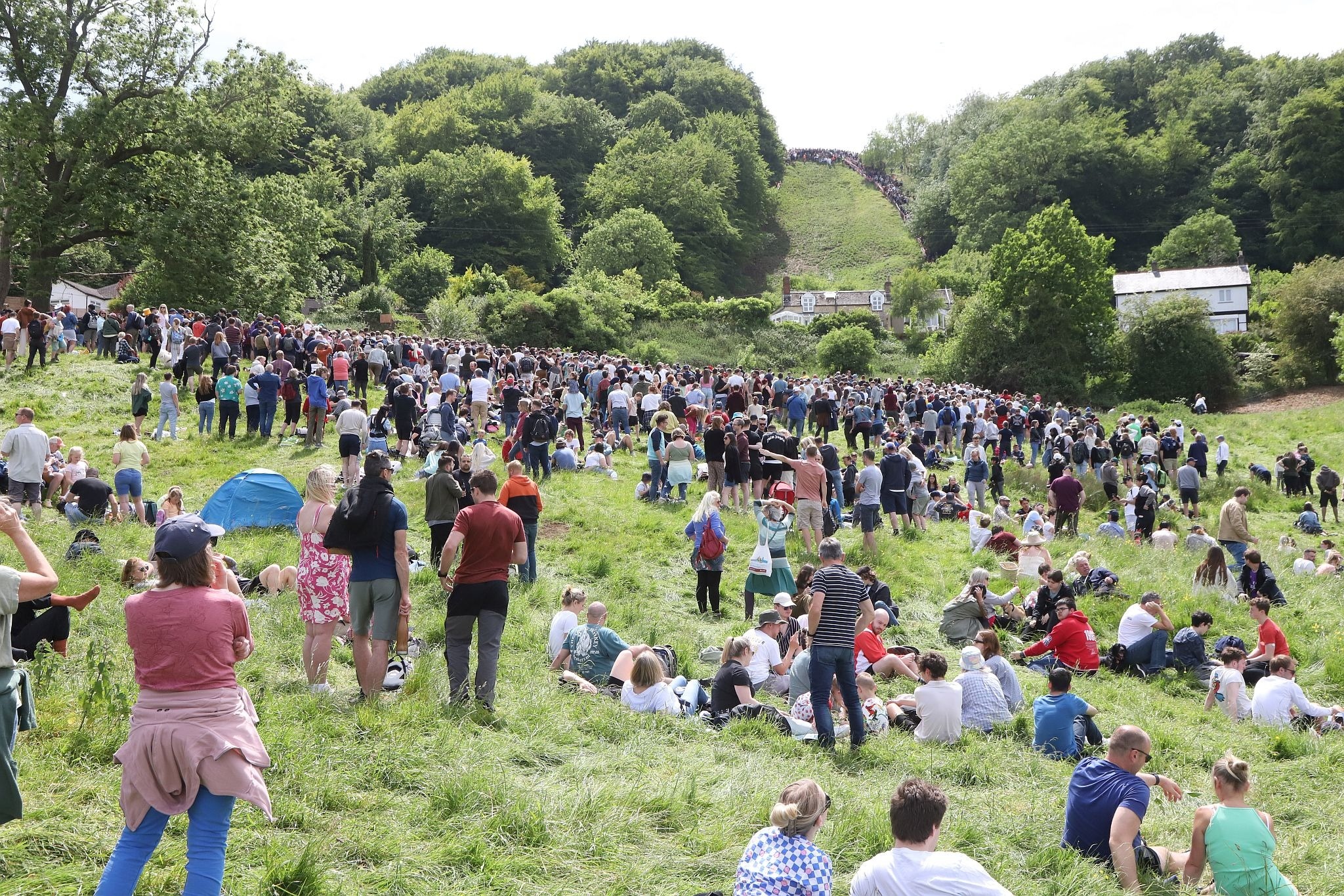 Crowds watch from the distance. Coopers Hill Cheese Rolling Race. 29-May-2023. Race downhill. Gloucestershire tradition.