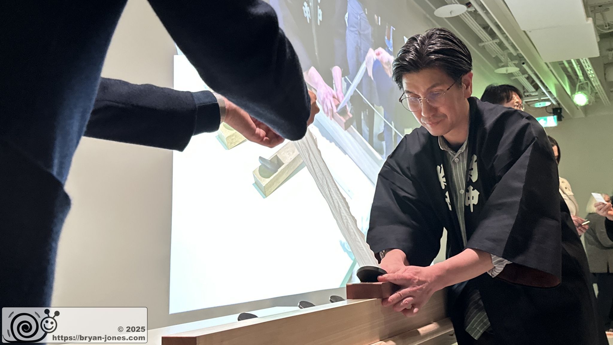 Carpenter planing wood. Japan House, London. 11-Mar-2025.