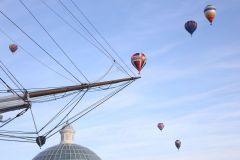 A flight of 46 hot air balloons taking part in the 2019 Lord Mayor’s Balloon Regatta fly over Greenwich passing the Cutty Sark ship and Old Royal Navy College by the River Thames early on the morning of  09-Jun-2019. City of London.