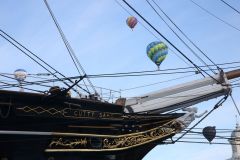 A flight of 46 hot air balloons taking part in the 2019 Lord Mayor’s Balloon Regatta fly over Greenwich passing the Cutty Sark ship and Old Royal Navy College by the River Thames early on the morning of  09-Jun-2019. City of London.