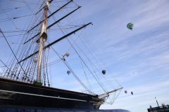 A flight of 46 hot air balloons taking part in the 2019 Lord Mayor’s Balloon Regatta fly over Greenwich passing the Cutty Sark ship and Old Royal Navy College by the River Thames early on the morning of  09-Jun-2019. City of London.