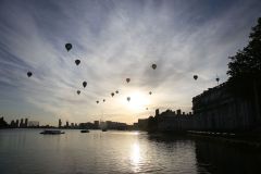 A flight of 46 hot air balloons taking part in the 2019 Lord Mayor’s Balloon Regatta fly over Greenwich passing the Cutty Sark ship and Old Royal Navy College by the River Thames early on the morning of  09-Jun-2019. City of London.