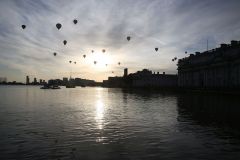 A flight of 46 hot air balloons taking part in the 2019 Lord Mayor’s Balloon Regatta fly over Greenwich passing the Cutty Sark ship and Old Royal Navy College by the River Thames early on the morning of  09-Jun-2019. City of London.