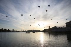 A flight of 46 hot air balloons taking part in the 2019 Lord Mayor’s Balloon Regatta fly over Greenwich passing the Cutty Sark ship and Old Royal Navy College by the River Thames early on the morning of  09-Jun-2019. City of London.