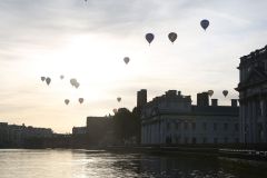 A flight of 46 hot air balloons taking part in the 2019 Lord Mayor’s Balloon Regatta fly over Greenwich passing the Cutty Sark ship and Old Royal Navy College by the River Thames early on the morning of  09-Jun-2019. City of London.