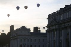 A flight of 46 hot air balloons taking part in the 2019 Lord Mayor’s Balloon Regatta fly over Greenwich passing the Cutty Sark ship and Old Royal Navy College by the River Thames early on the morning of  09-Jun-2019. City of London.